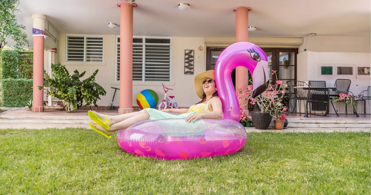 Woman with hat on a flamingo inflatable smiling